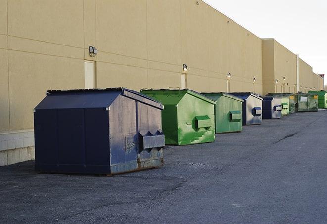 a construction worker unloading debris into a blue dumpster in Capistrano Beach